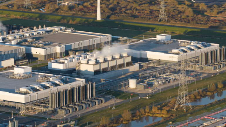 Striking aerial drone photo of a massive data center's cooling infrastructure. Highlights the immense scale, water usage, and energy consumption required for hyperscale computing.