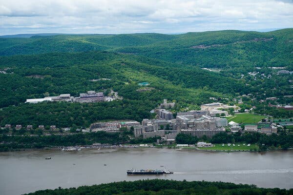 Buildings on a university campus dot a hillside located next to a river.