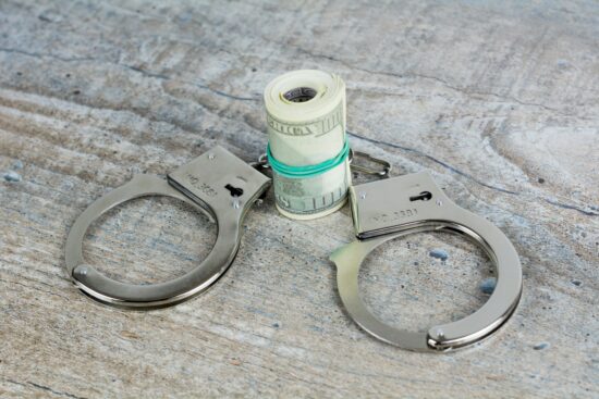 Handcuffs and usa dollar banknotes on wooden background. More of my photos and videos Adobe Stock:http://bit.ly/3RqlciK More of my photos and videos Shutterstock: https://www.shutterstock.com/g/ALEKSANDRBERDYUGIN My email: bermix999@gmail.com