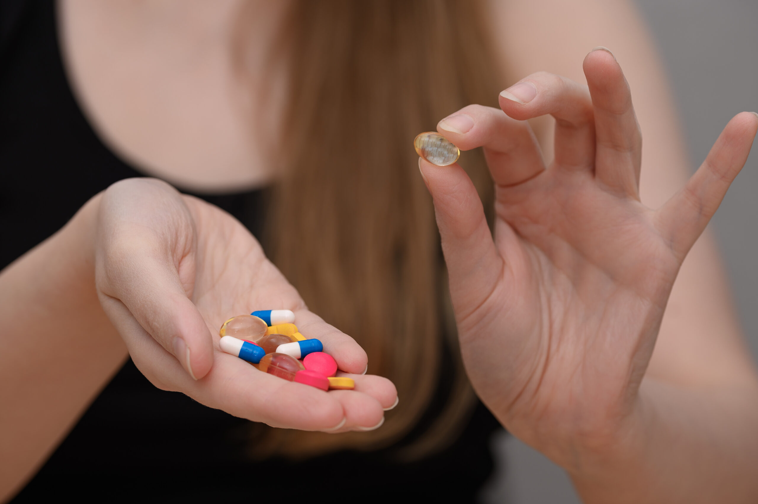 Various medicines and vitamins held in a woman's hand, take medicines
