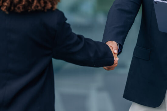 Two business professionals shaking hands in an office setting