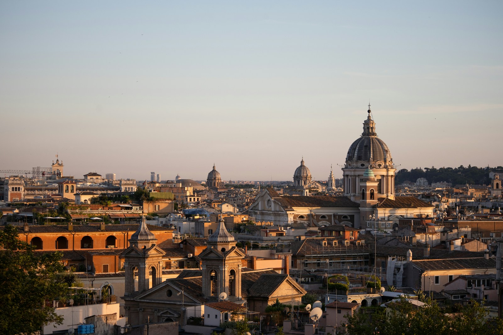 Golden hour bathes Rome’s sea of domes and bell towers, stretching toward the horizon in warm haze.