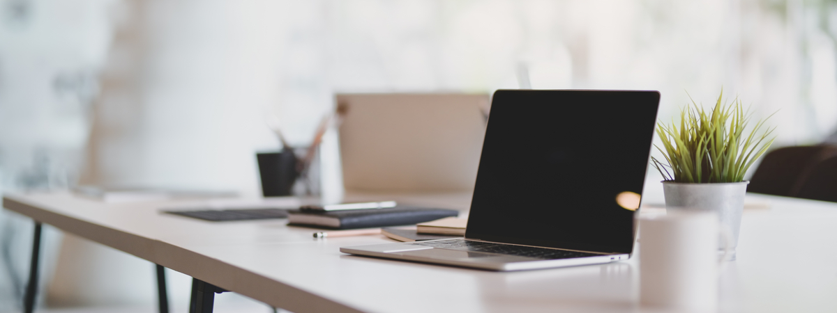 Open blank laptop in modern workplace with office supplies and decorations on white table