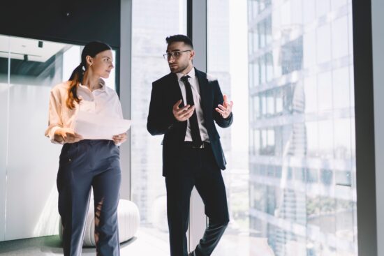 Serious,Colleagues,In,Formal,Outfits,Discussing,Documents,While,Walking,Along