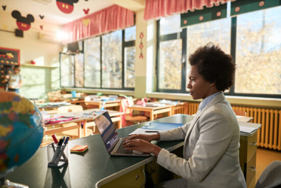 Teacher working on laptop in the classroom.
