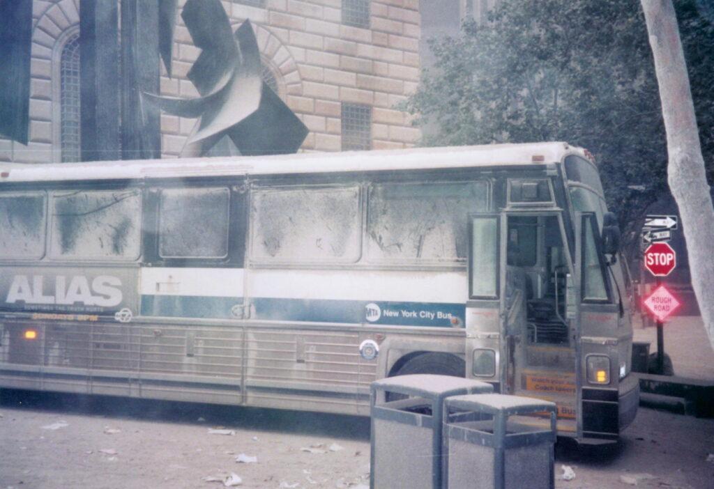 Dust-covered MTA city bus parked on a debris-strewn Lower Manhattan street