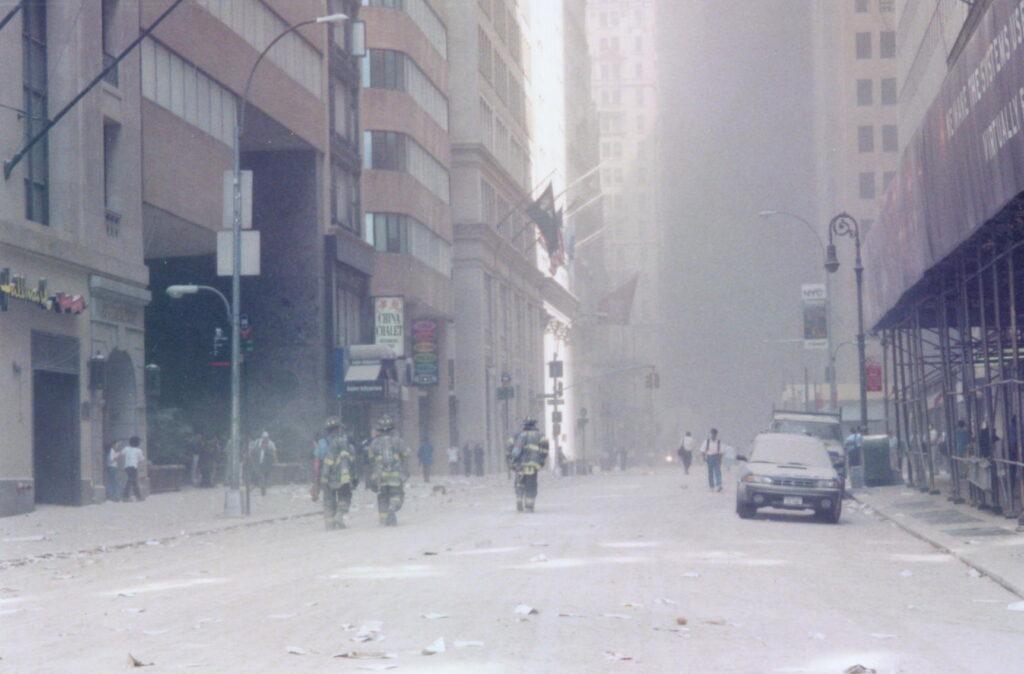 Firefighters walking through a debris-covered Lower Manhattan street after the towers collapsed