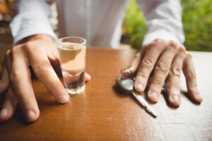 Is Being Drunk in Public a Crime in California? What Penal Code § 647(f) Really Requires 8 Shot glass of alcohol and car keys on a table in front of a person.