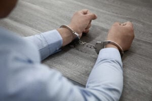 https-kirakosianlaw-com-wp-content-uploads-2026-09-selective-focus-shot-male-hands-handcuffs-wooden-table-1-300x200-jpg