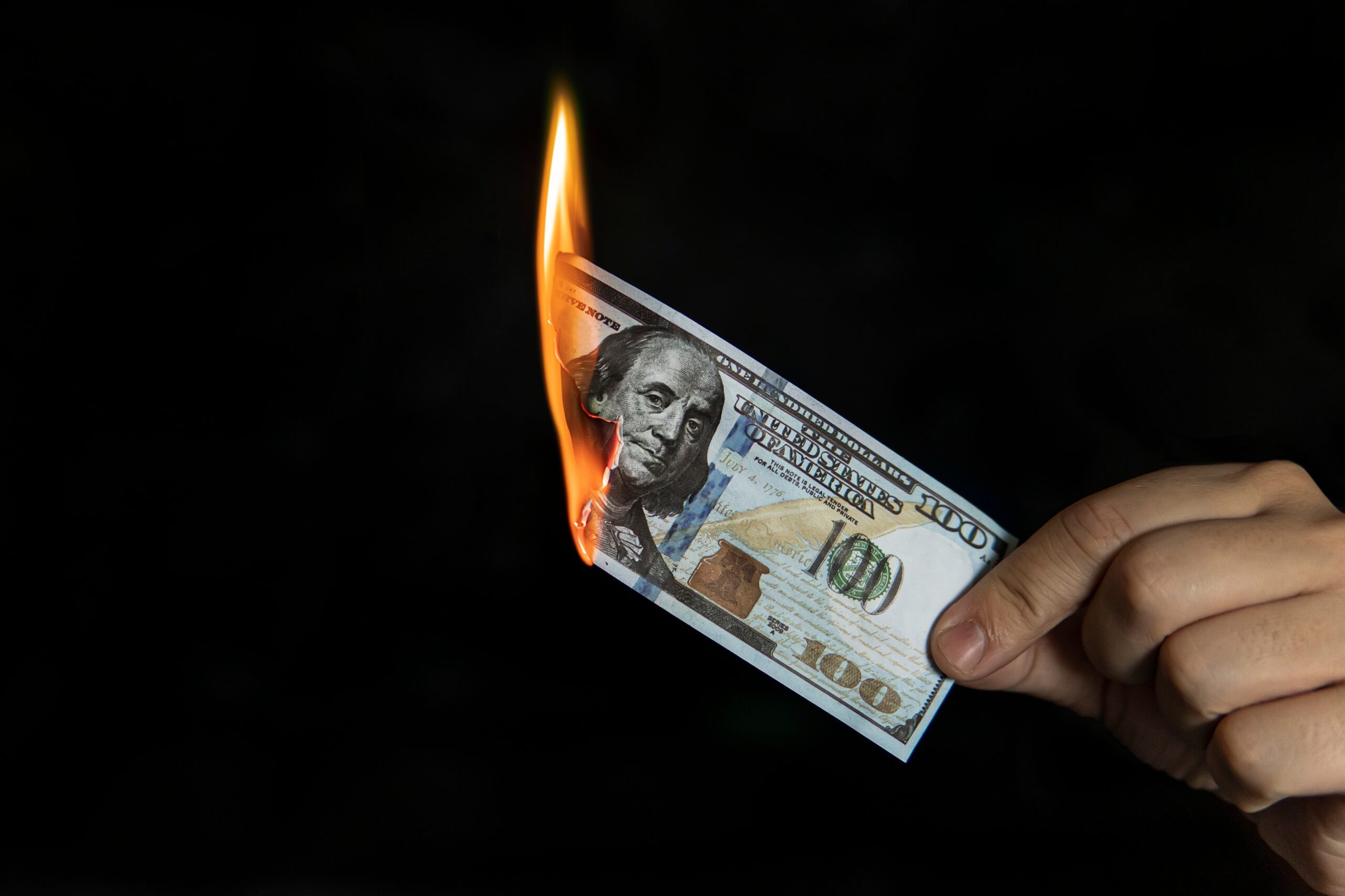 Human,Hand,Holding,A,Burning,100,Dollar,Bill.,Concept,Of
