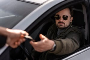 Can Police Arrest You for Asking If They Have Reasonable Suspicion? 4 Driver handing a card or document to someone through the open car window.