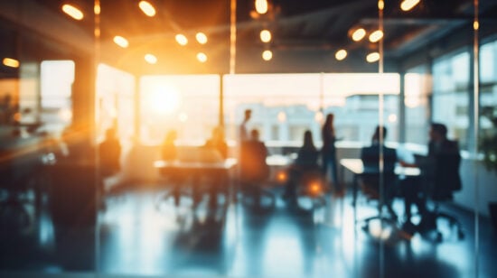 Blurred image of business people walking in modern office with sunlight.